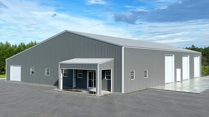 Gray metal industrial building with a covered entrance and multiple garage doors.
