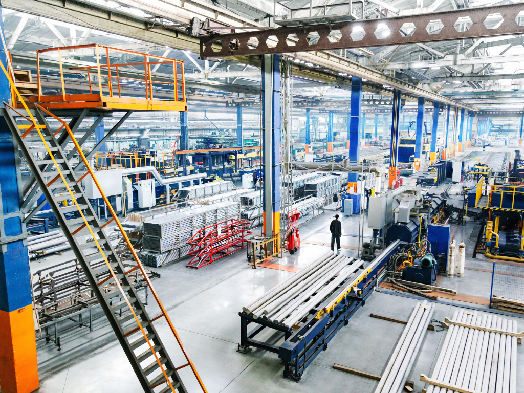 Factory interior with production lines, machinery, and a person standing in the aisle.