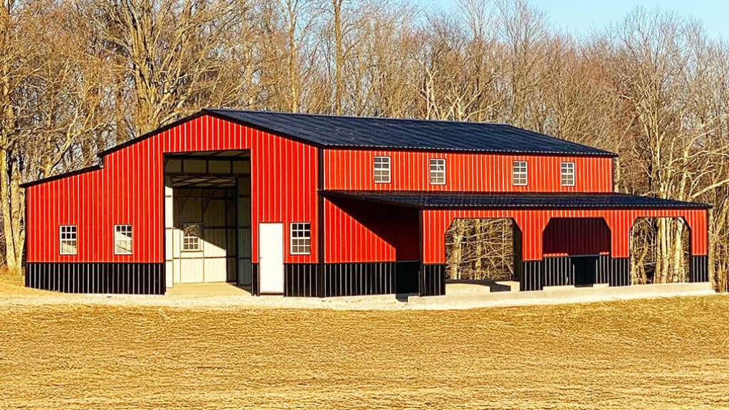 Black metal building with brown garage doors and trim, set on concrete, blue sky.