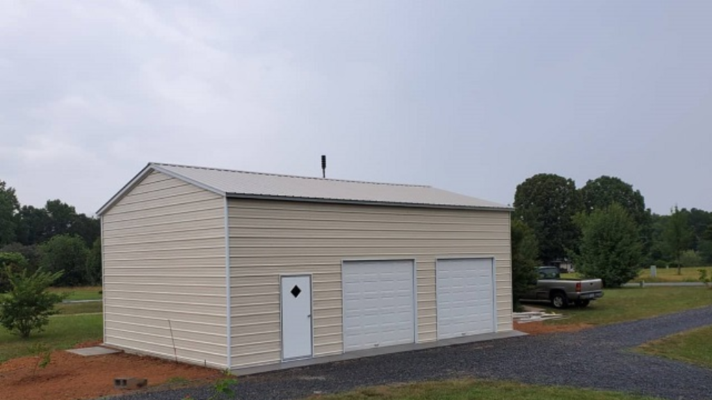 Three-bay garage with grey siding, white garage doors, and a side door with a blue roof.