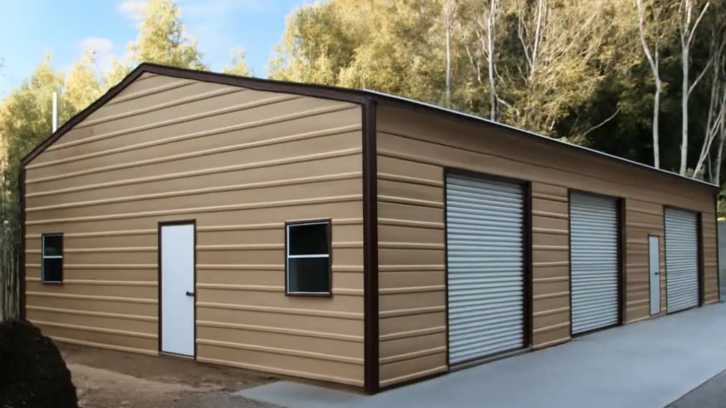 Three-bay garage with grey siding, white garage doors, and a side door with a blue roof.