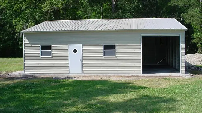 Tan metal garage with white door and open bay, set on grass.