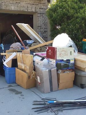 Pile of packed boxes and discarded items outside a garage.