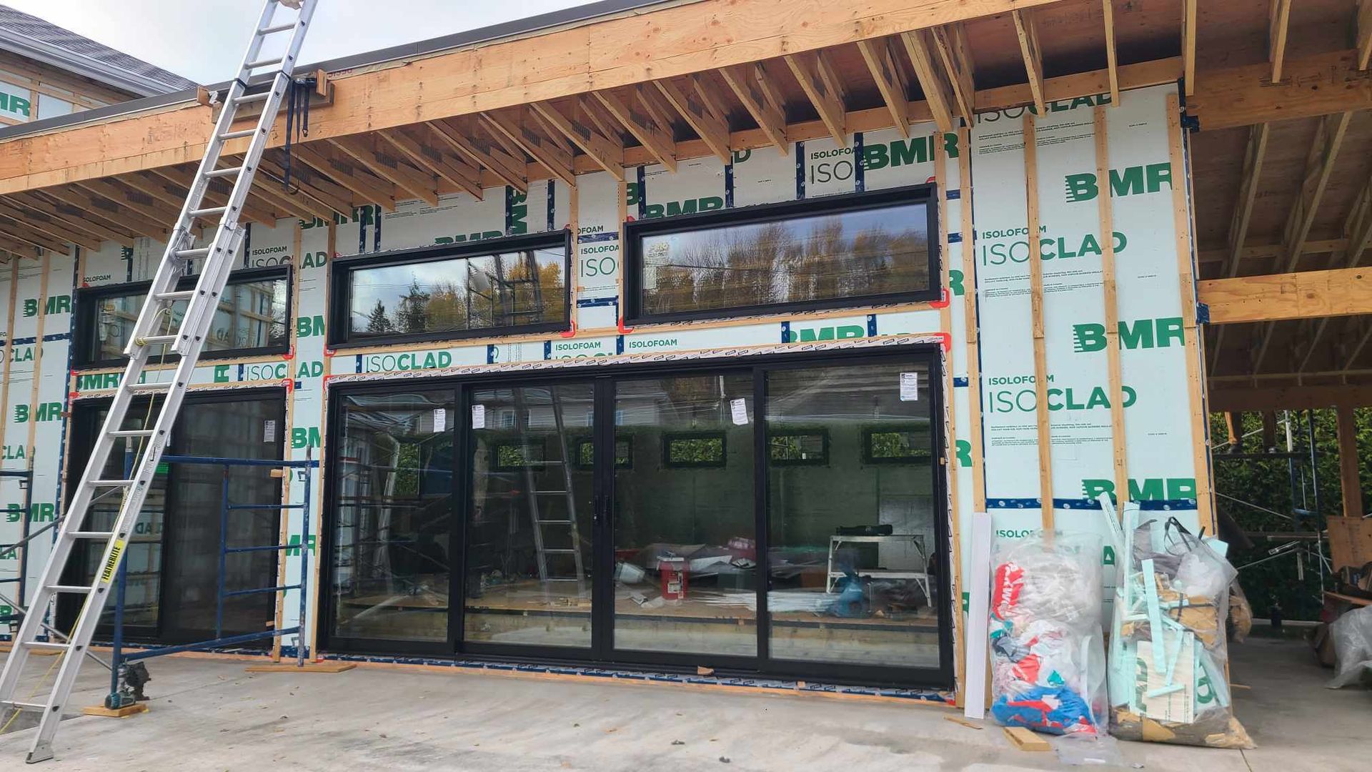 Extérieur d'un bâtiment en construction, montrant des fenêtres et une échelle.