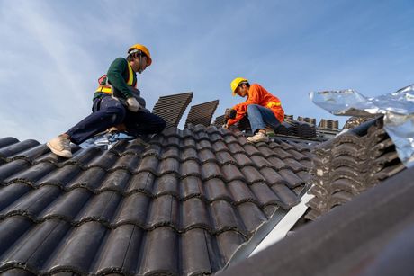 Two men are working on the roof of a house.