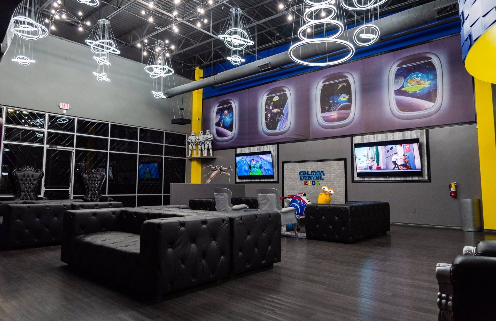 A large room with a lot of furniture and televisions on the wall.