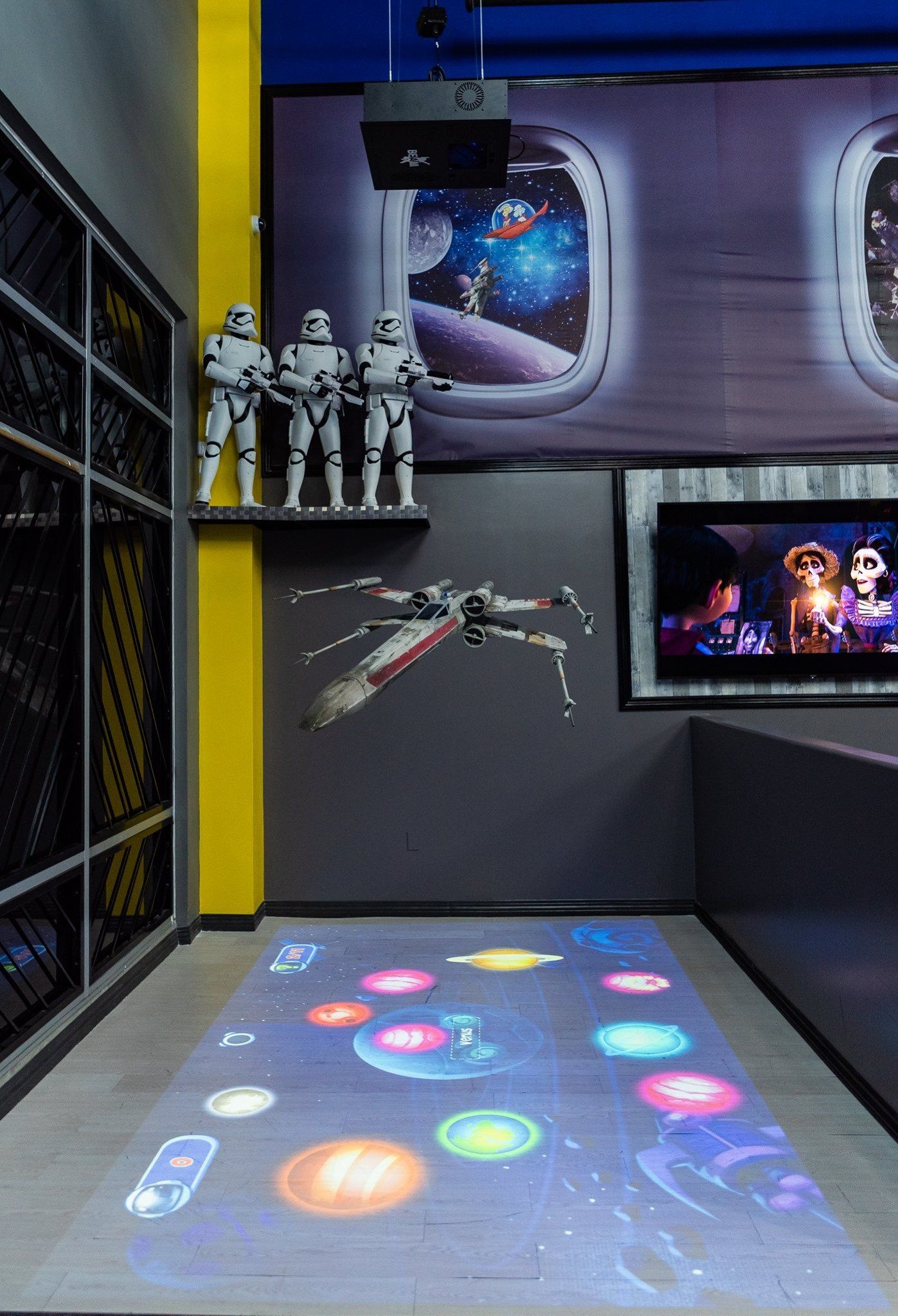 A room with a projector on the floor and a star wars poster on the wall.