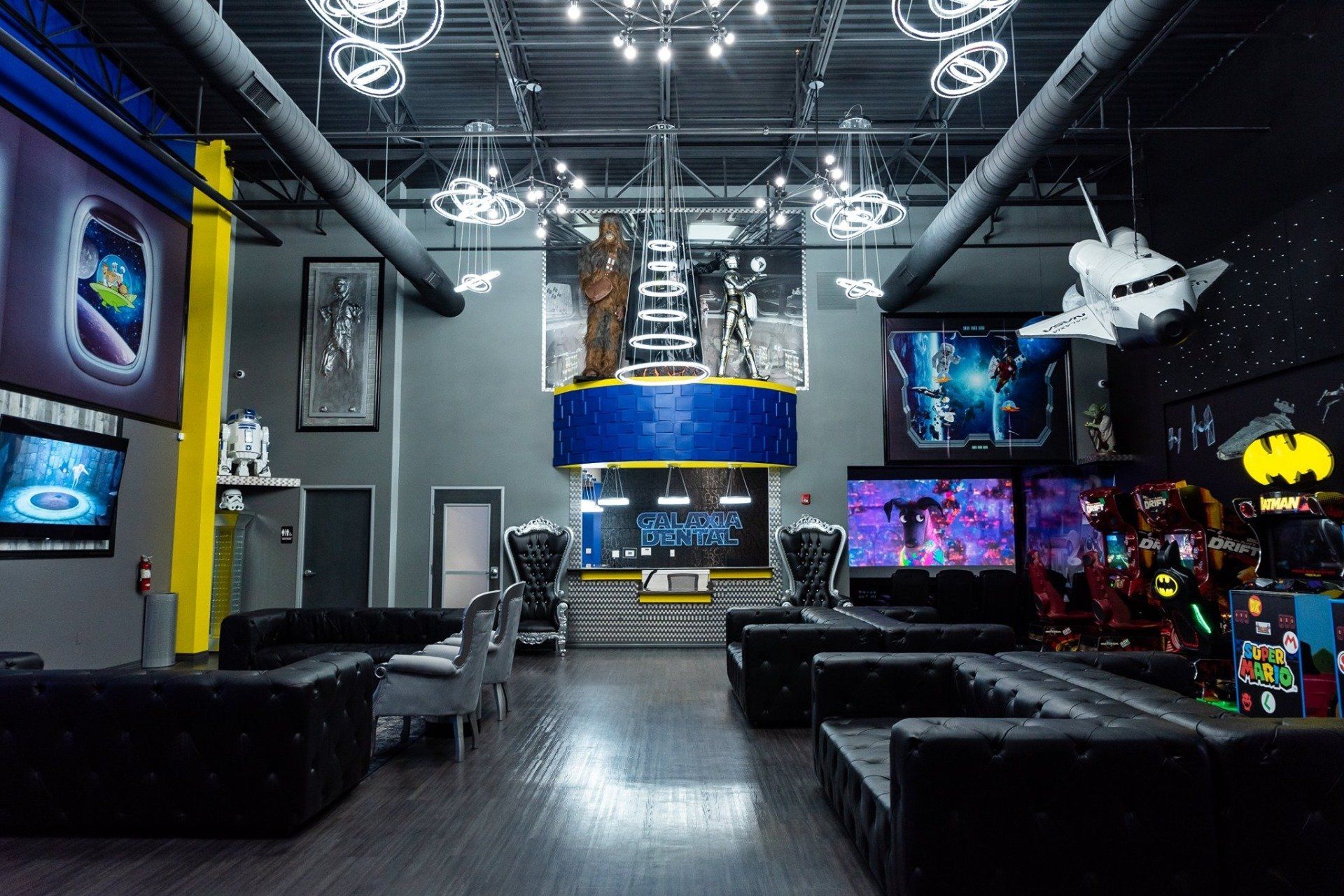 A large room with a lot of furniture and a batman sign on the wall.