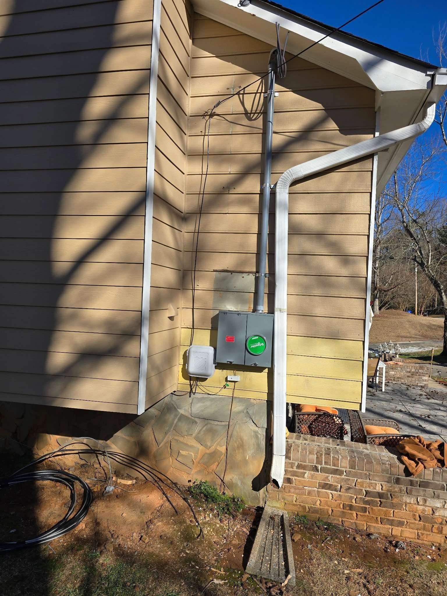 Electrical box on a tan house exterior, with a conduit and gutter.