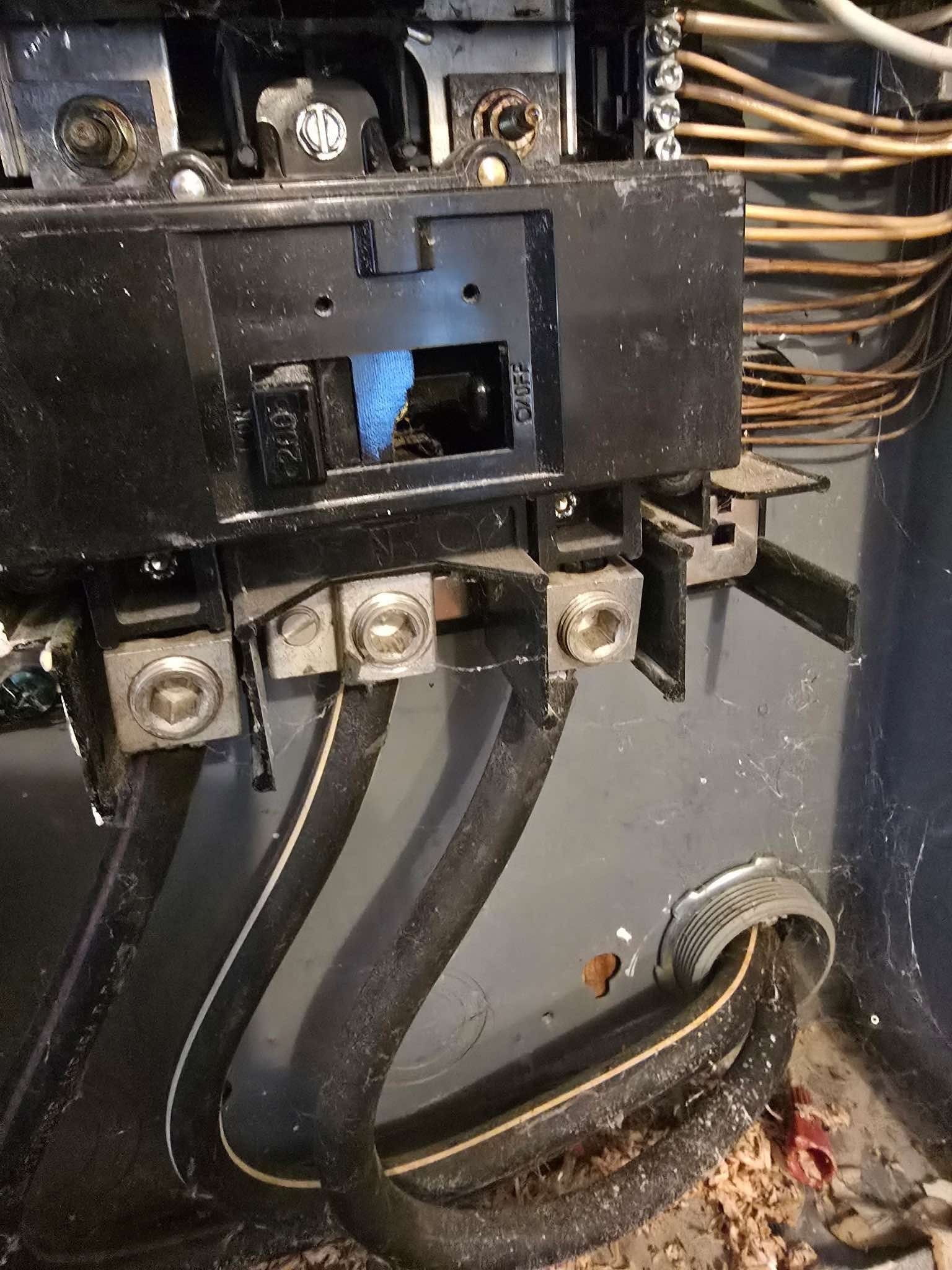 Electrical panel with black circuit breakers and thick black wires connected to lugs.