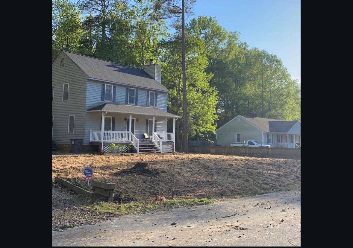 A house with a porch and a lot of dirt in front of it.