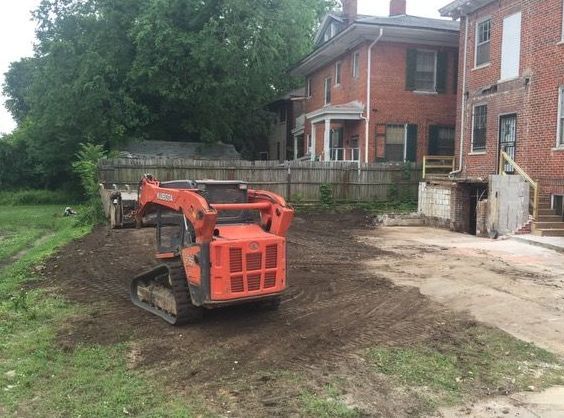 A white building is being demolished with a yellow excavator in the background