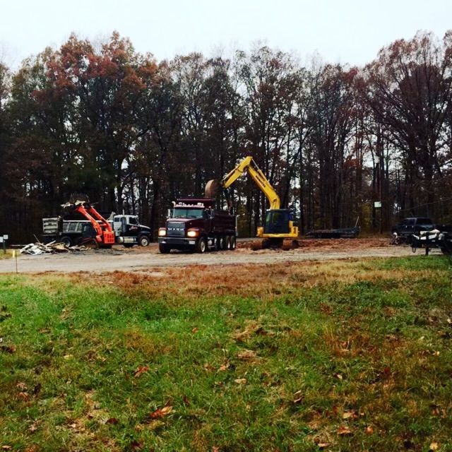 A truck is driving down a dirt road next to an excavator