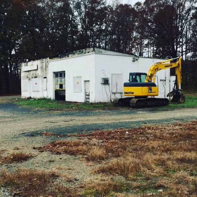 A yellow komatsu excavator is parked in front of a white building