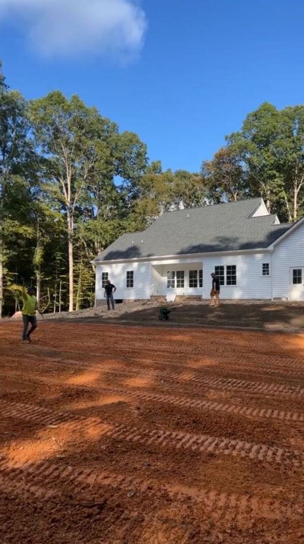 A white house is being built in the middle of a dirt field.
