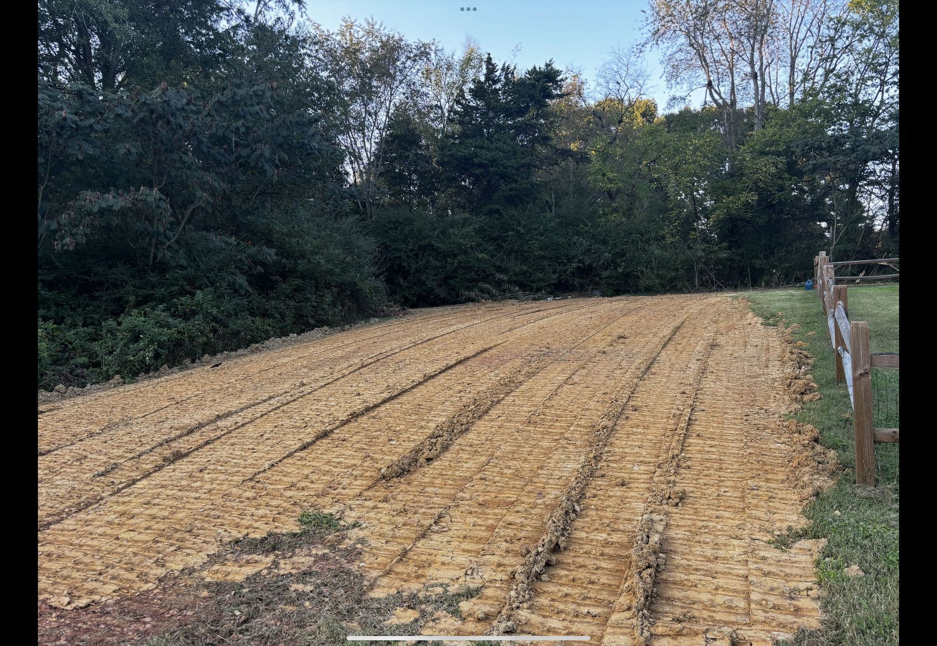 A large field of dirt with trees in the background.