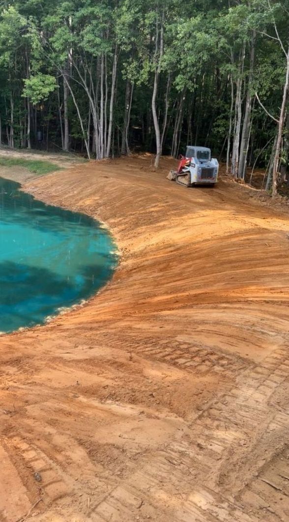 A truck is driving down a dirt road next to a lake.