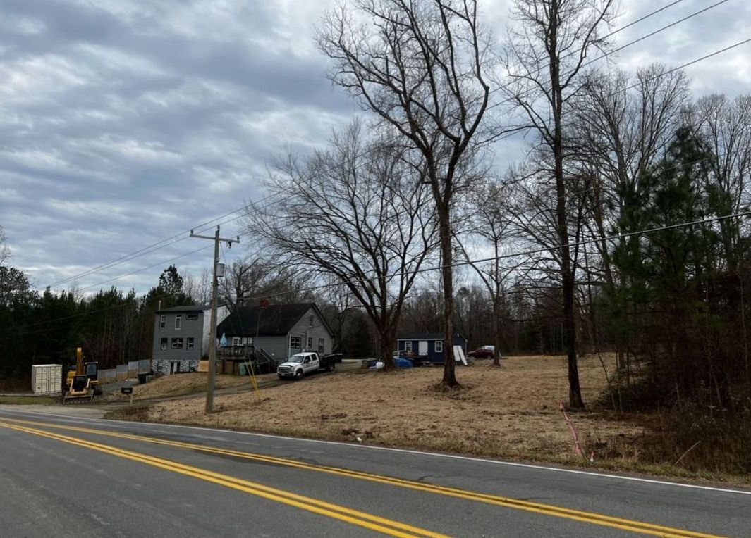 A road with a lot of trees on the side of it and a house in the background.