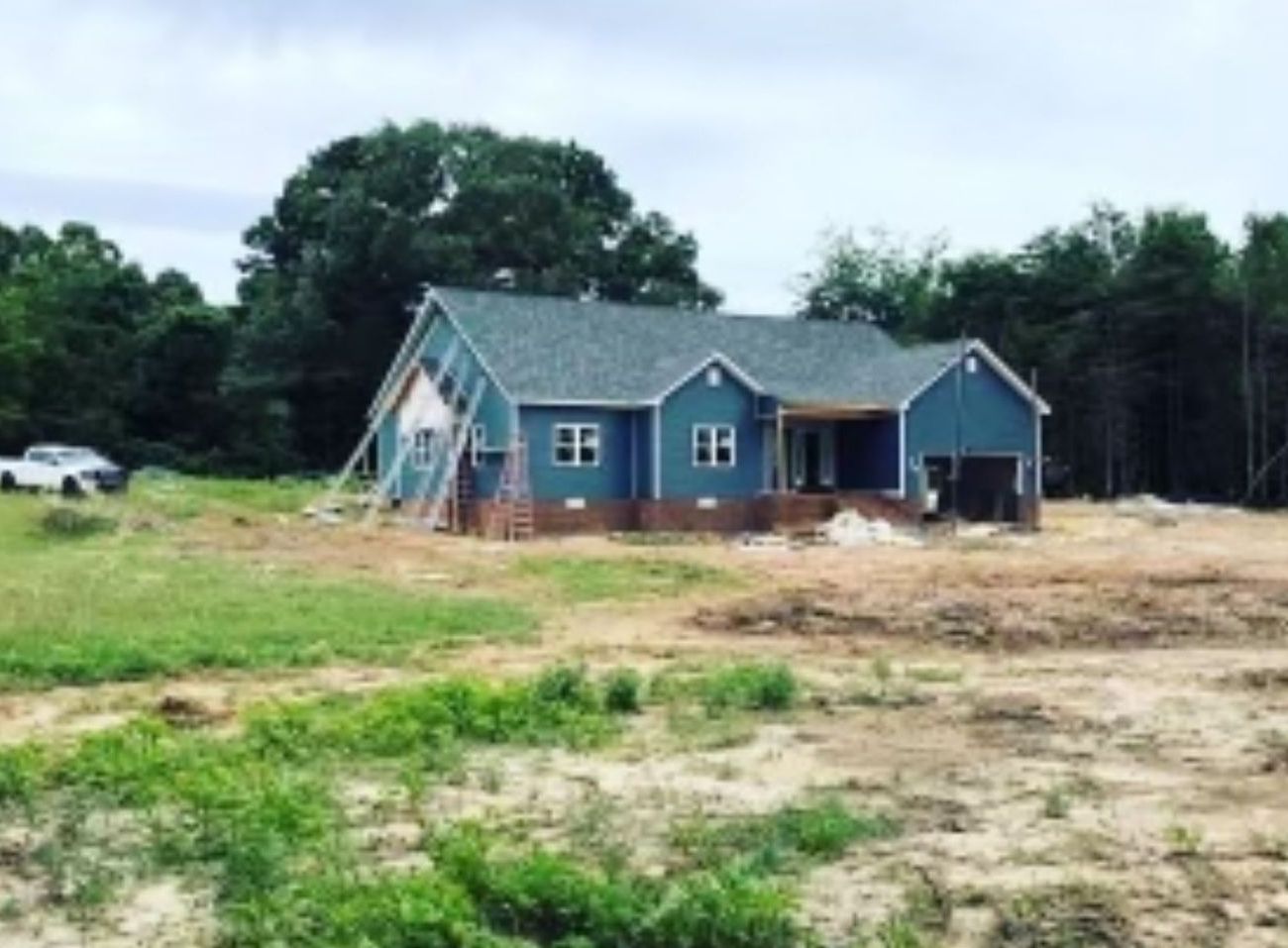 A blue house is being built in the middle of a field.