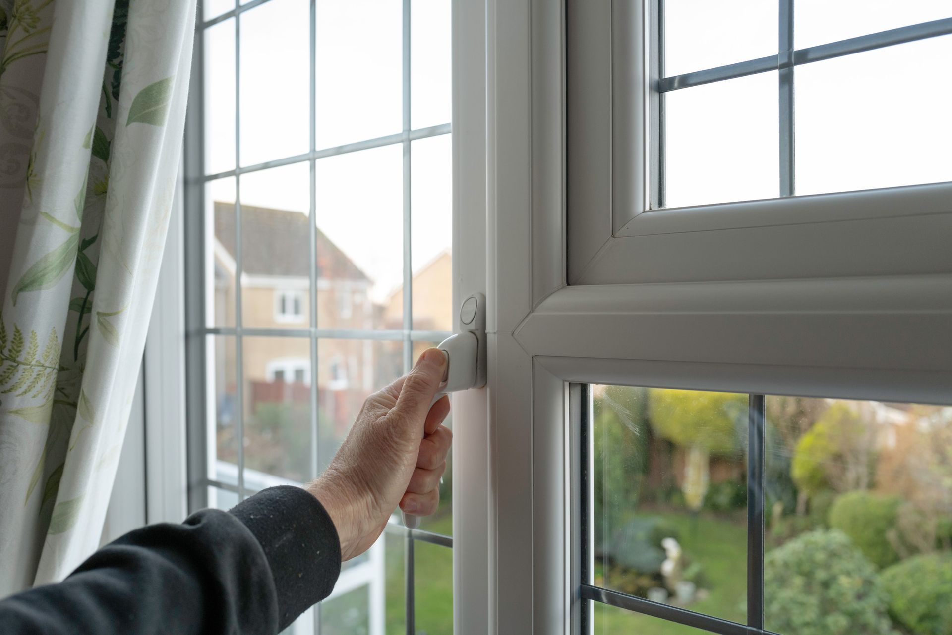 A person is opening a window in a house.