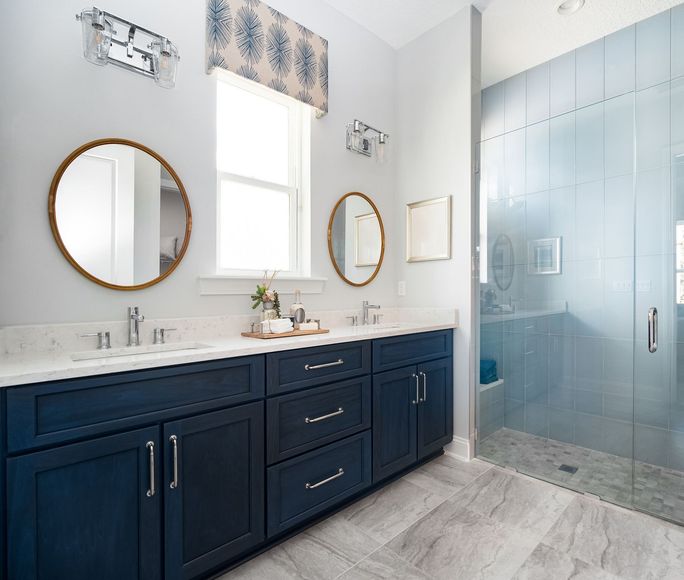 A bathroom with two sinks , two mirrors and a walk in shower.