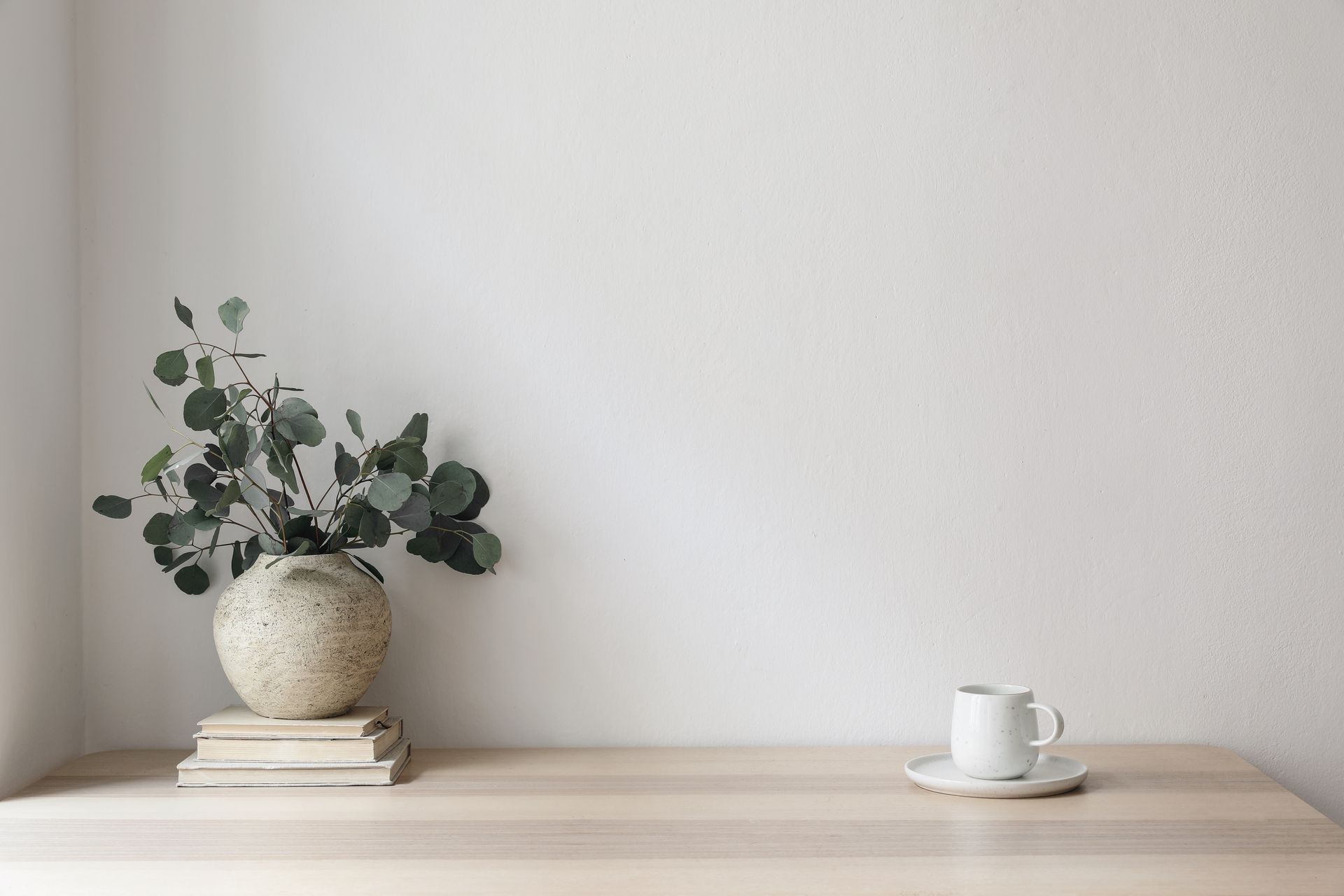 A vase of flowers is sitting on top of a wooden table next to a cup of coffee. — The Home Assembly In Avoca Beach, NSW
