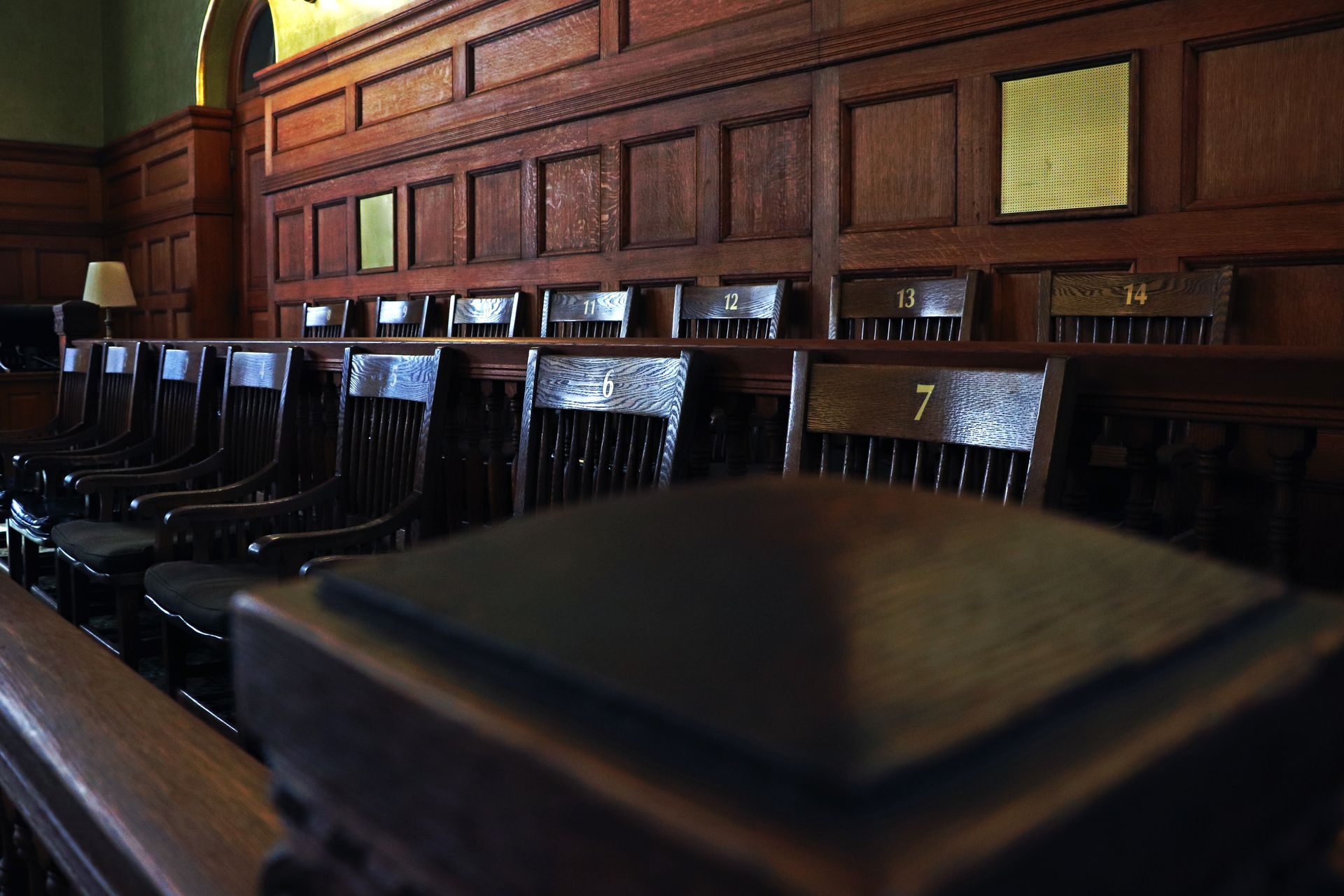 A man is sitting at a table with a wooden family and a gavel.