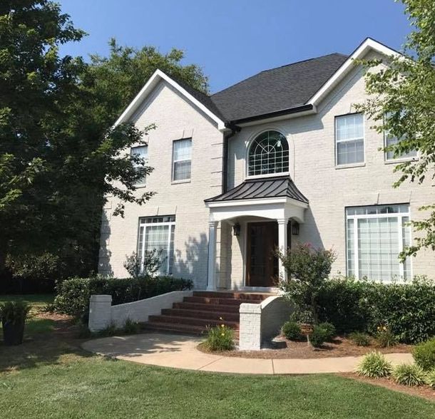 A large white brick house with a black roof