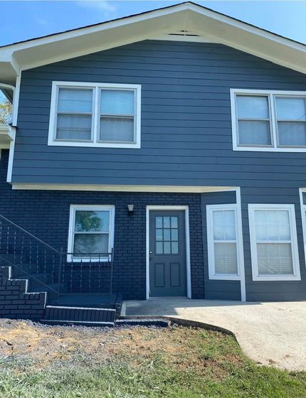 The front of a house with a blue siding and white windows.