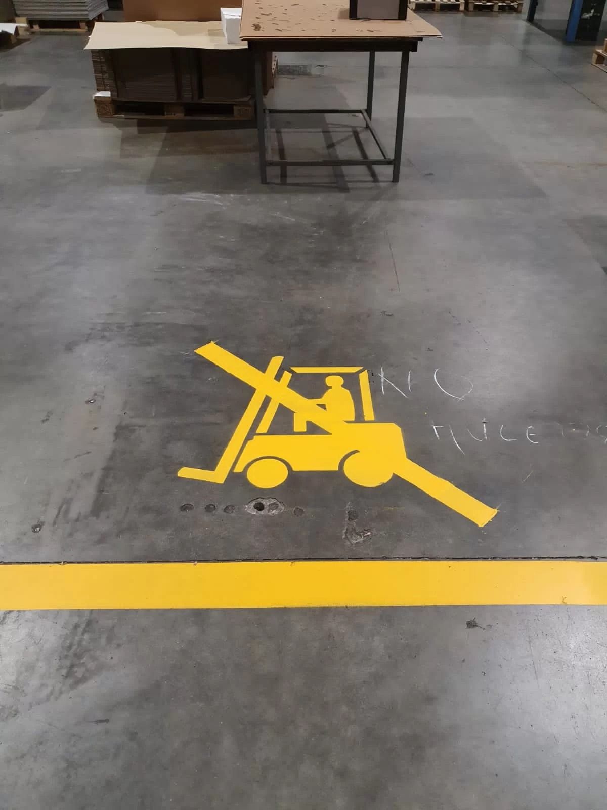 Segnaletica orizzontale gialla raffigurante un carrello elevatore barrato, che indica