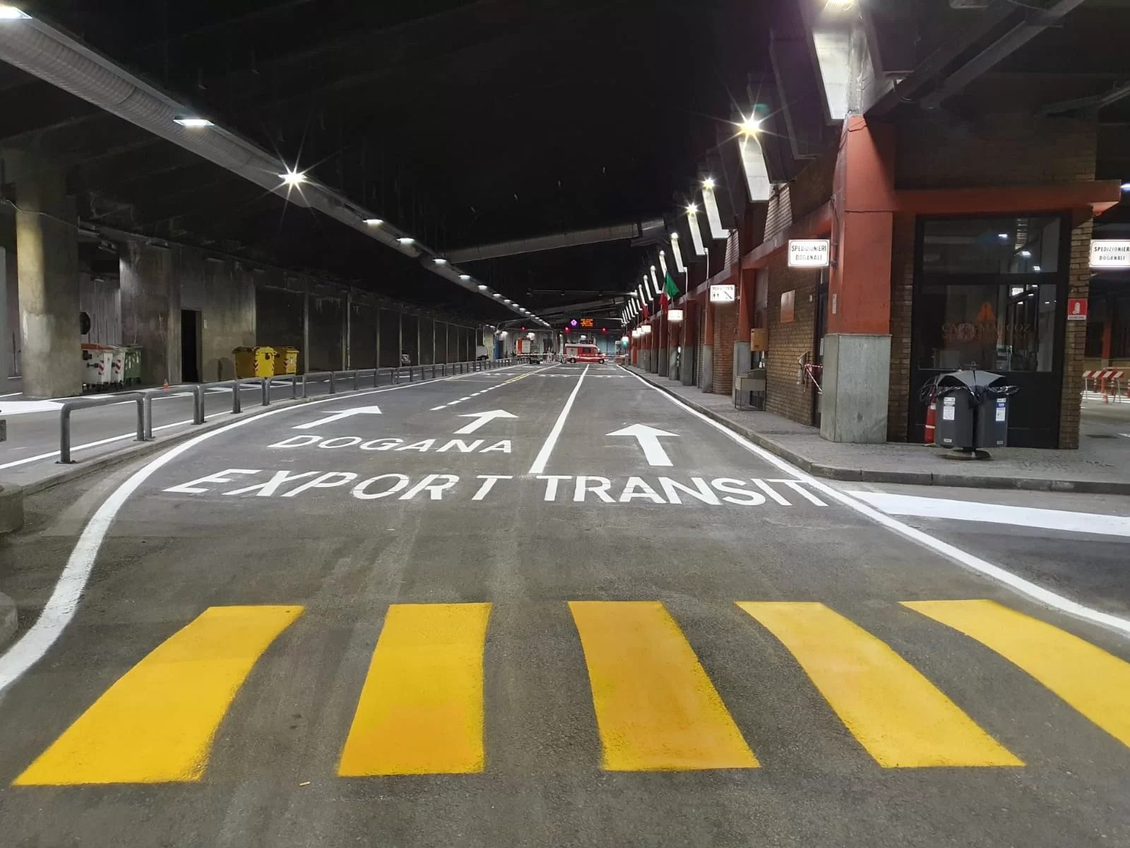 Una corsia asfaltata con strisce pedonali gialle e segnaletica bianca