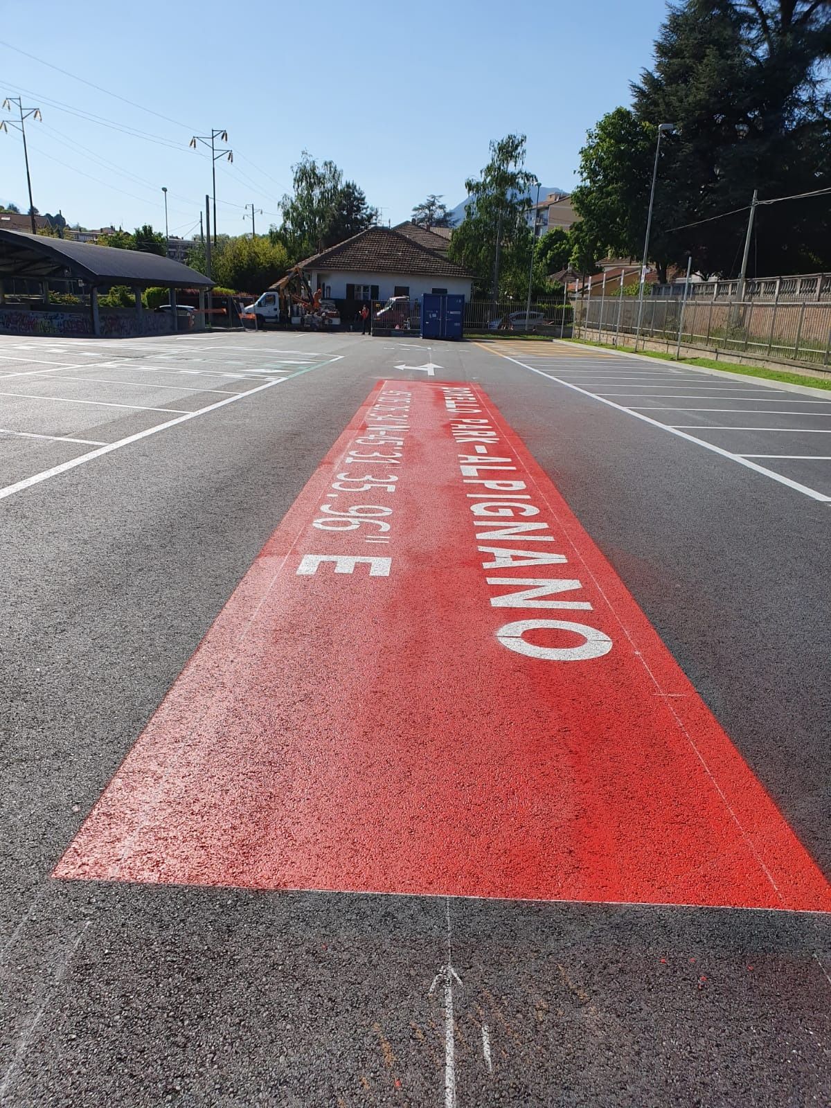 Su un parcheggio asfaltato è presente una zona rettangolare dipinta di rosso acceso con la scritta bianca