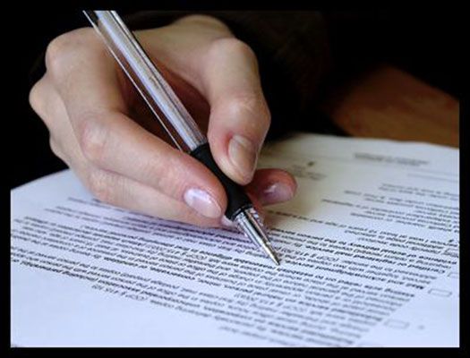 Mano con penna che scrive su un documento. Primo piano.