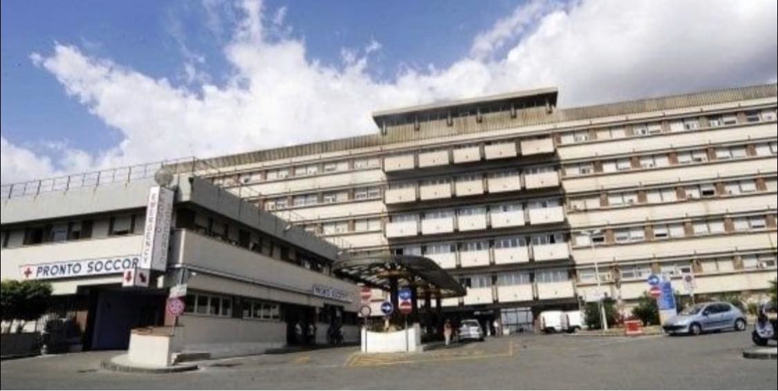 Esterno dell'ospedale con cielo nuvoloso.