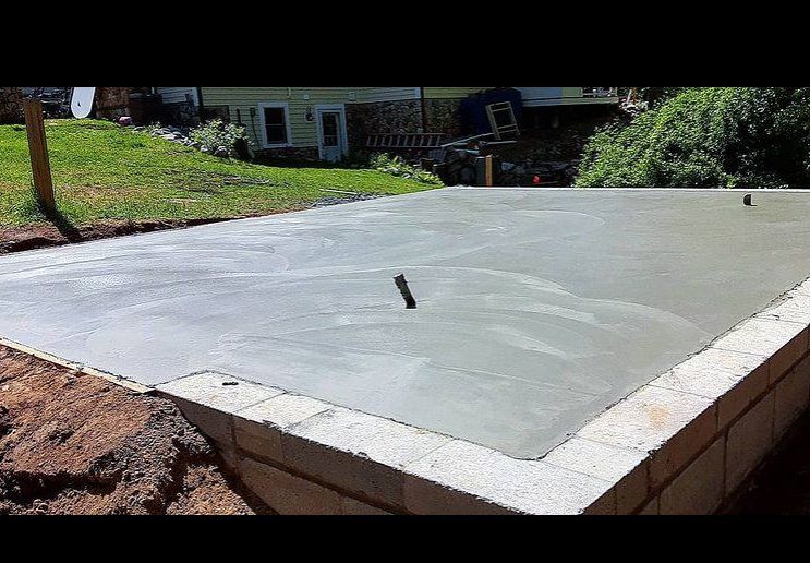 Newly poured concrete slab in the front yard of a house.  The slab will hold a small garage or shed.
