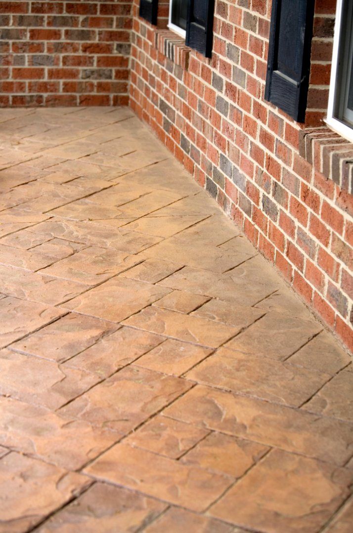 Backyard concrete patio with concrete stamps.  The patio leads up to a brick house.