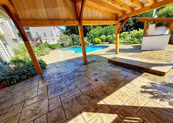 Covered patio with a stamped concrete design in a backyard pool area in Peterborough.
