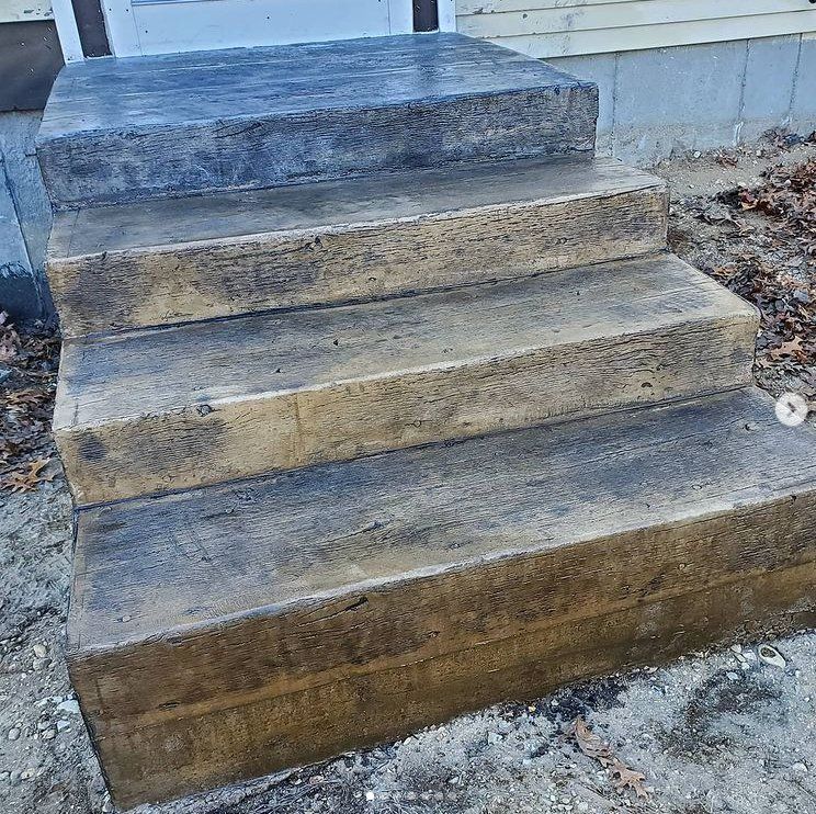 Picture of concrete steps leading from a concrete patio up to a deck.