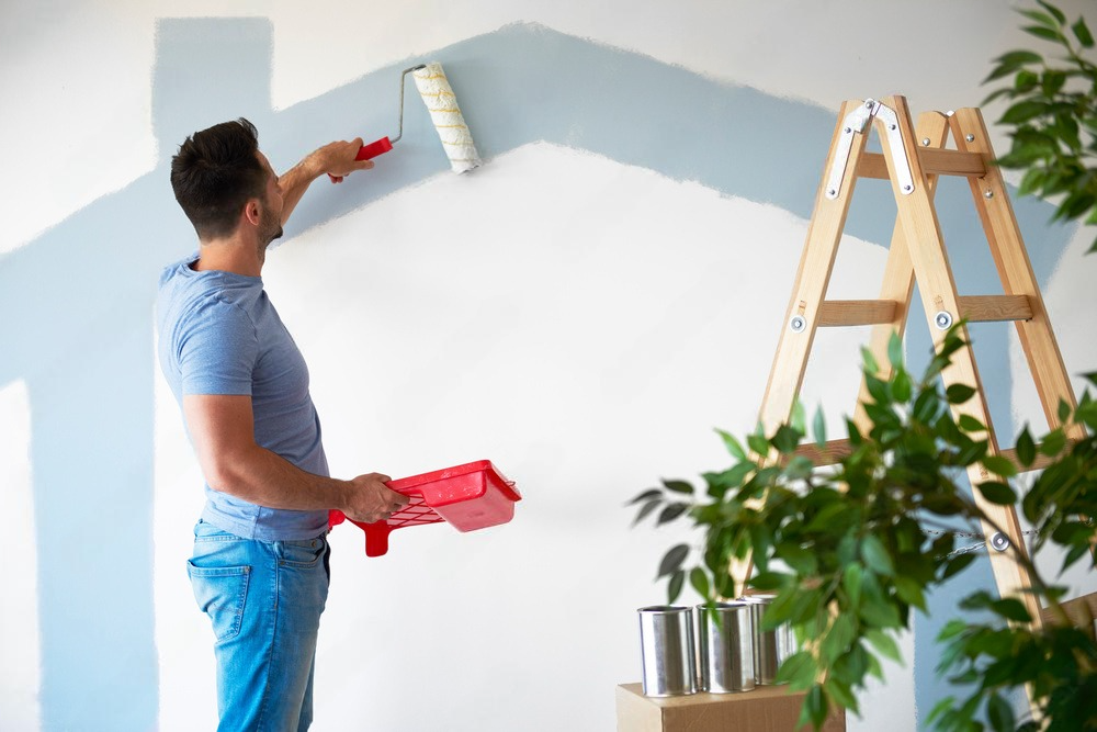 a man is painting a wall with a paint roller