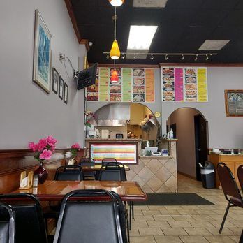 A restaurant with tables and chairs and a surfboard in the background.