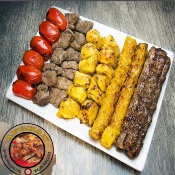 A white plate topped with meat , potatoes and tomatoes