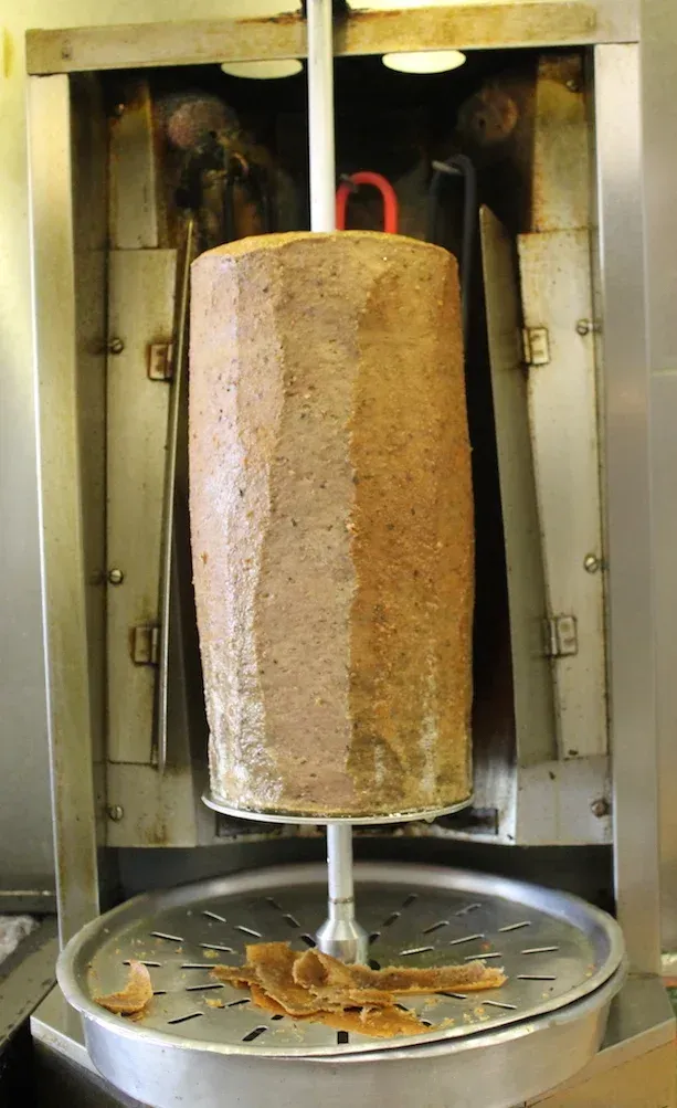 A plate of food with meat and vegetables on a wooden table.