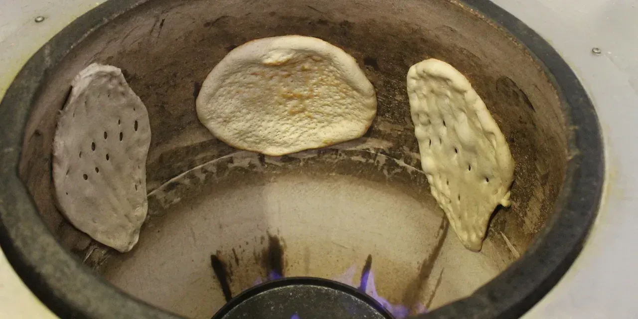 A close up of a kebab on a cutting board with vegetables.