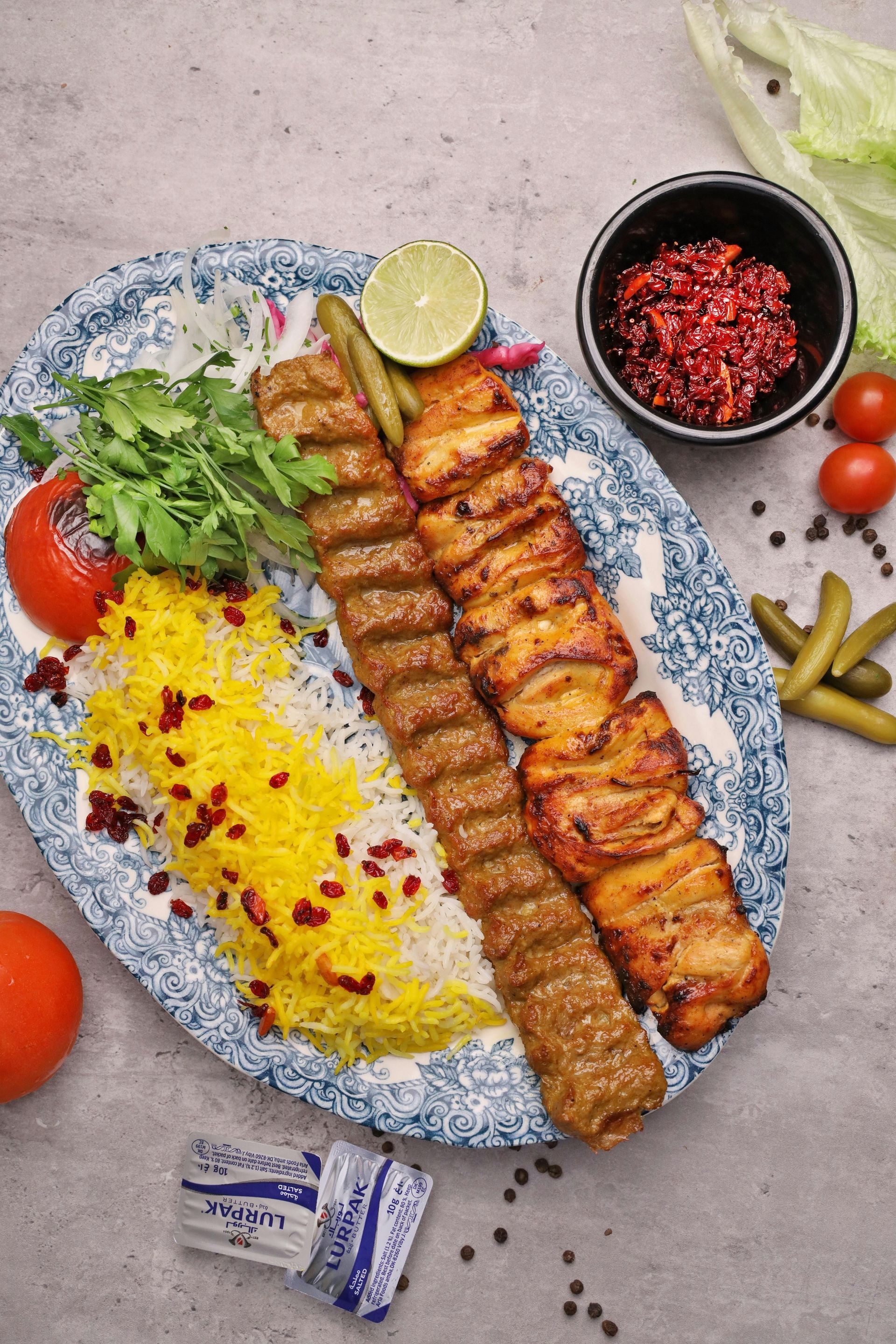 A plate of food with rice , meat and vegetables on a table.