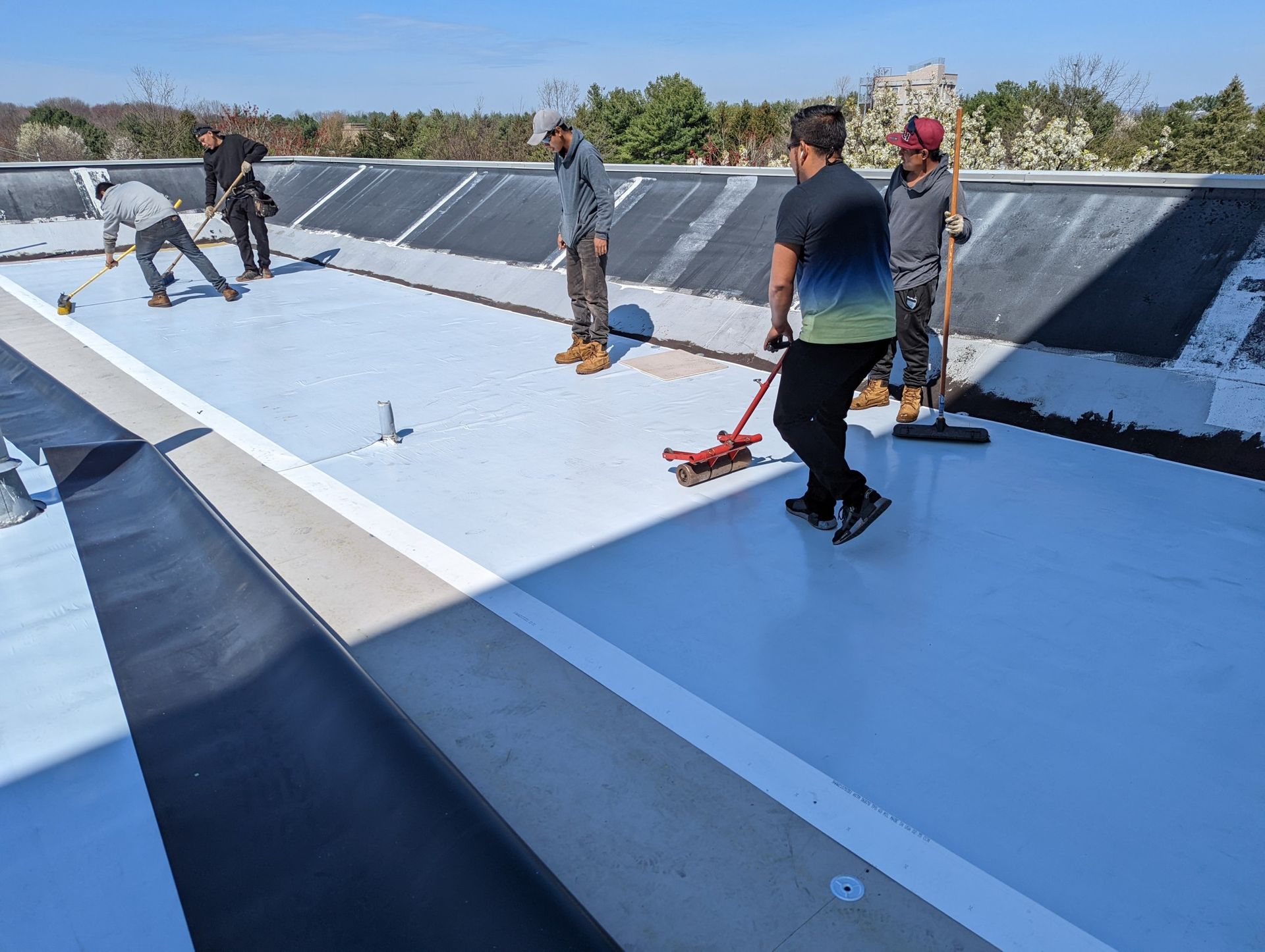 Workers installing a light blue pool liner. Men use tools to smooth and secure the material on a concrete base.