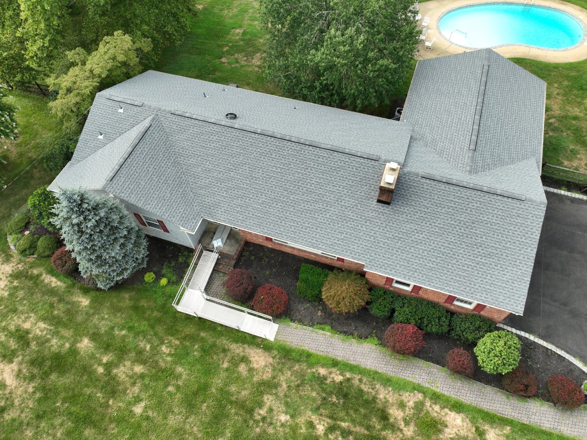 Aerial view of a gray-roofed house with a swimming pool in the yard.