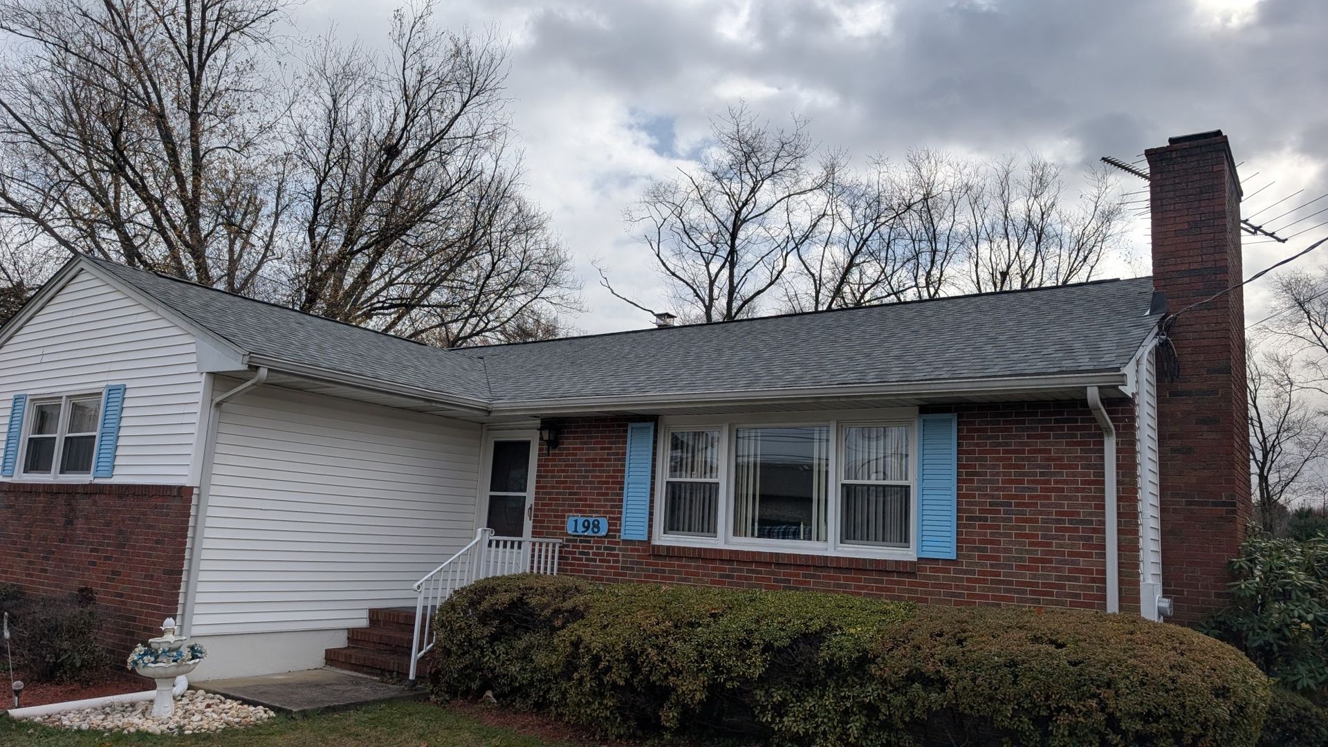 Woman in straw hat smiles, holding wine glass near a lake.