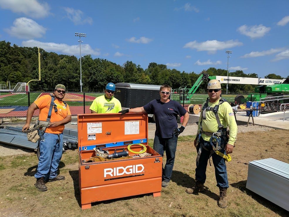 Woman in straw hat smiles, holding wine glass near a lake.