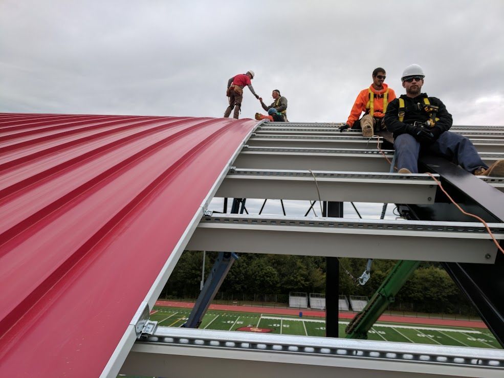 Woman in straw hat smiles, holding wine glass near a lake.
