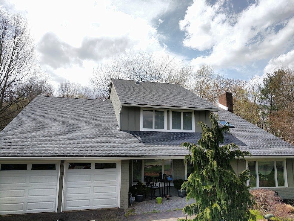 Woman in straw hat smiles, holding wine glass near a lake.